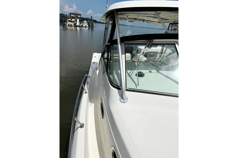 Slide: The Image of 2005 Pursuit 2870 Walkaround boat docked on calm water, showcasing sleek design. - 25