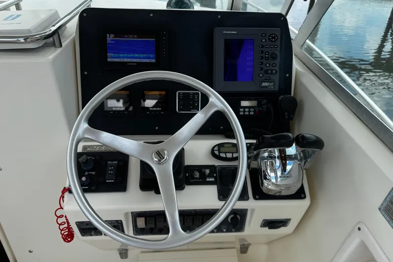Slide: The Image of 2005 Pursuit 2870 Walkaround boat dashboard with steering wheel and navigation controls. - 28