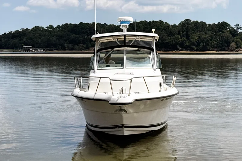 Slide: The Image of 2005 Pursuit 2870 Walkaround boat on calm water with forested shoreline background. - 3