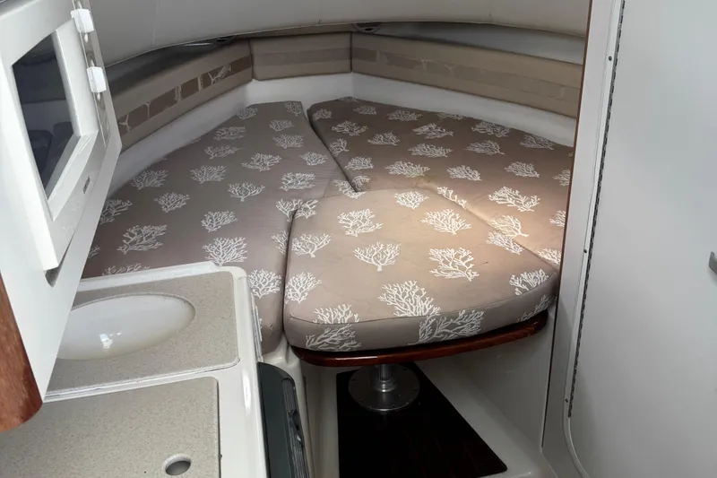 Slide: The Image of 2005 Pursuit 2870 Walkaround cabin interior with patterned cushions and compact kitchenette. - 36