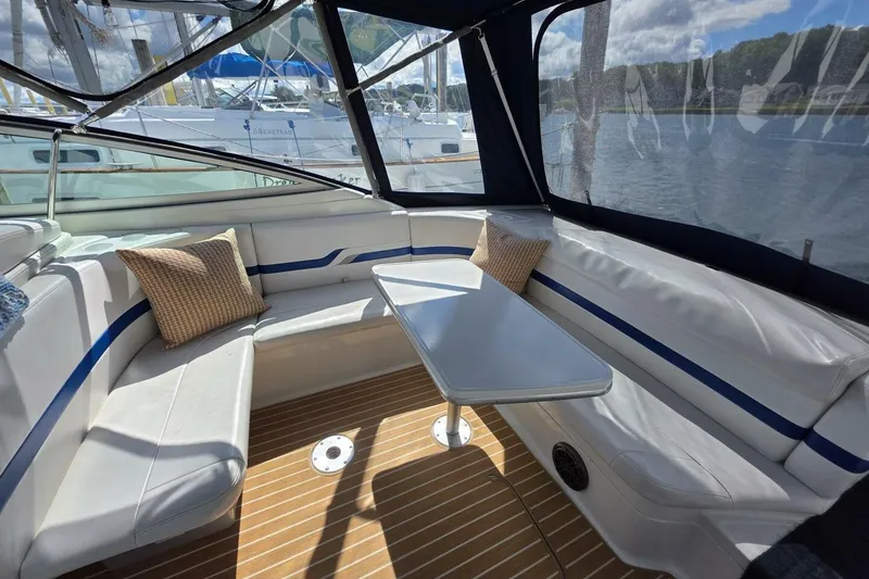 Slide: The Image of 2002 Formula 330 Sun Sport boat interior with cushioned seating and table, docked by the water. - 11