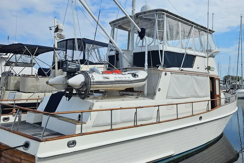 The Image of 1989 Grand Banks 42 Classic yacht docked at marina, featuring upper deck and dinghy. - 0