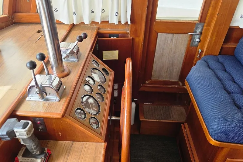 Slide: The Image of Interior helm of 1989 Grand Banks 42 Classic yacht with wooden controls and blue seating. - 20