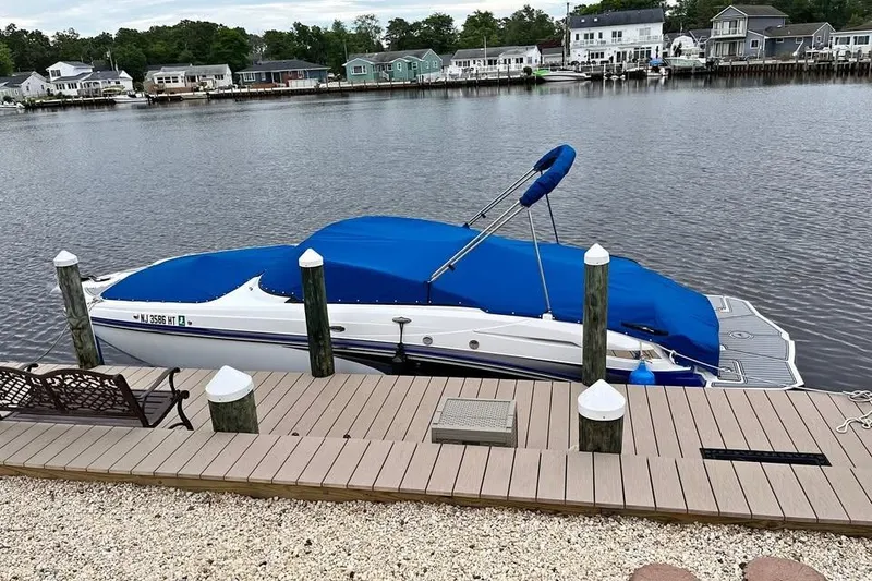 The Image of 2021 Monterey M6 boat docked by a serene waterfront with blue cover. - 0