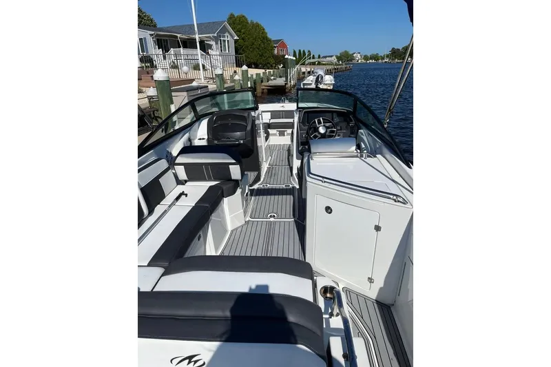 Slide: The Image of 2021 Monterey M6 boat interior with seating, steering wheel, and dockside view. - 2