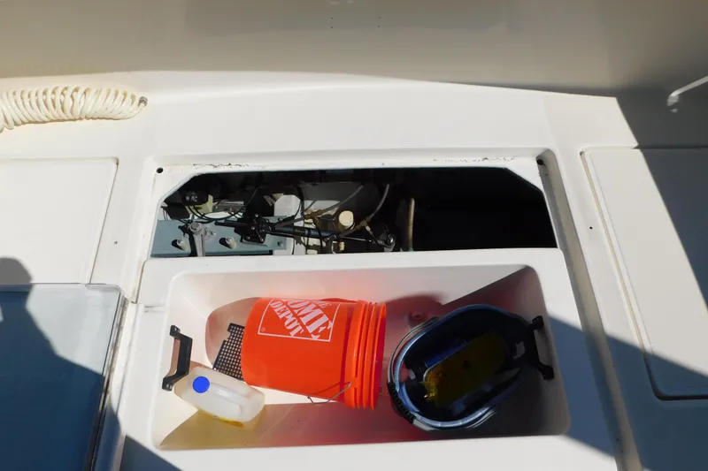 Slide: The Image of 1993 Tiara Yachts 3100 Open storage compartment with cleaning supplies and engine access. - 17