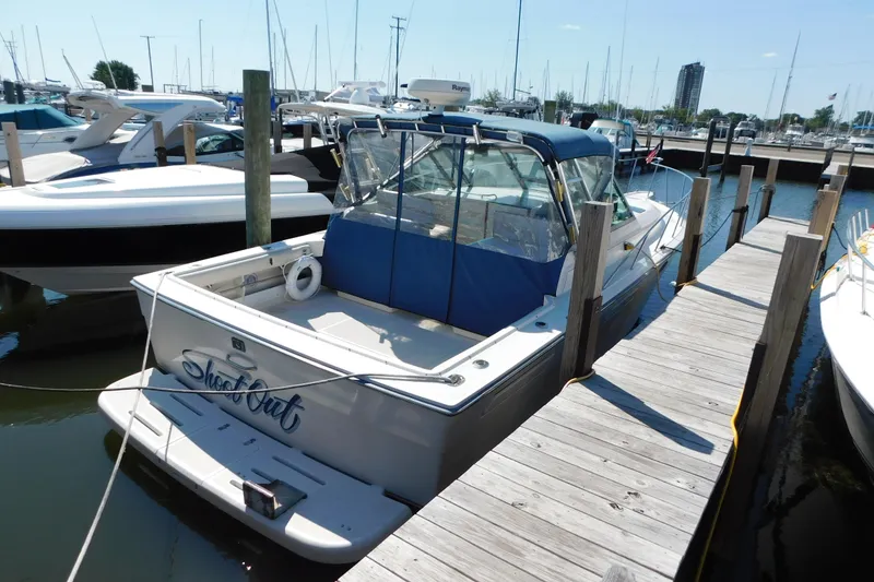 Slide: The Image of 1993 Tiara Yachts 3100 Open docked at marina, featuring blue canopy and spacious deck. - 2