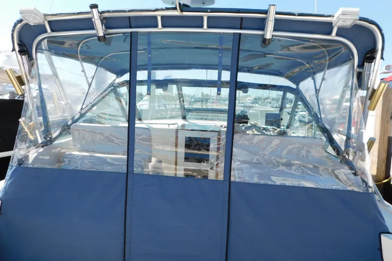 Slide: The Image of 1993 Tiara Yachts 3100 Open with blue canvas enclosure at marina. - 26