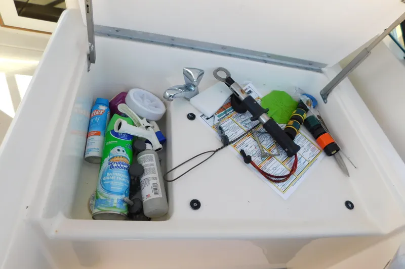 Slide: The Image of Storage compartment on a 1993 Tiara Yachts 3100 Open, containing cleaning supplies and tools. - 30