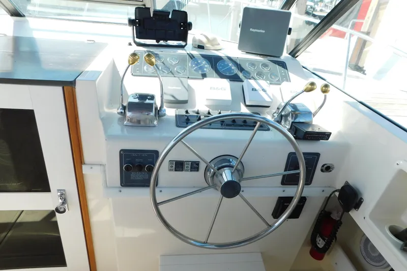 Slide: The Image of 1993 Tiara Yachts 3100 Open helm with steering wheel and navigation controls. - 32