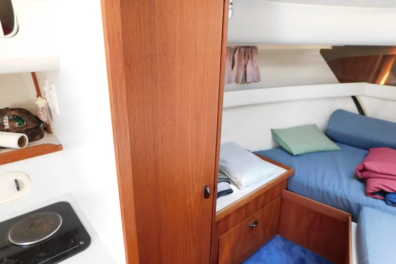 Slide: The Image of 1993 Tiara Yachts 3100 Open cabin interior with bed, wooden cabinetry, and compact kitchen area. - 65