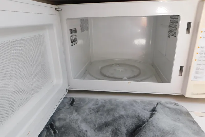 Slide: The Image of Open microwave oven with a marble countertop in a kitchen setting. - 74