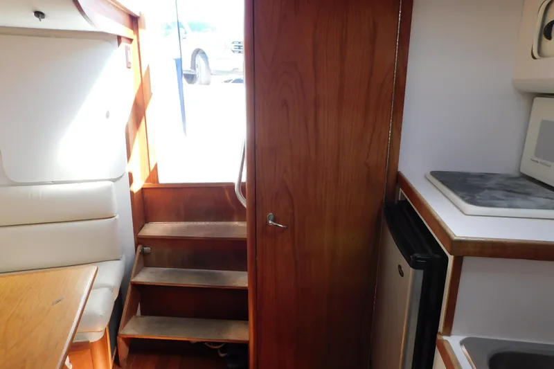 Slide: The Image of Interior of 1993 Tiara Yachts 3100 Open, featuring stairs, kitchenette, and seating area. - 80