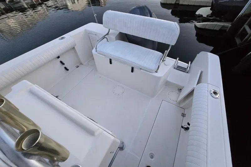 Slide: The Image of 2003 Robalo R230 Center Console boat interior with seating and storage, docked by calm water. - 4