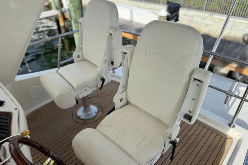 Slide: The Image of Luxurious helm seats on 1998 Sea Ray 480 Sedan Bridge yacht, featuring elegant white upholstery. - 13