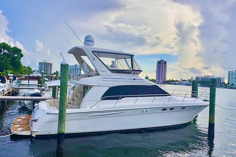 Slide: The Image of 1998 Sea Ray 480 Sedan Bridge yacht docked in a marina with cityscape background. - 2