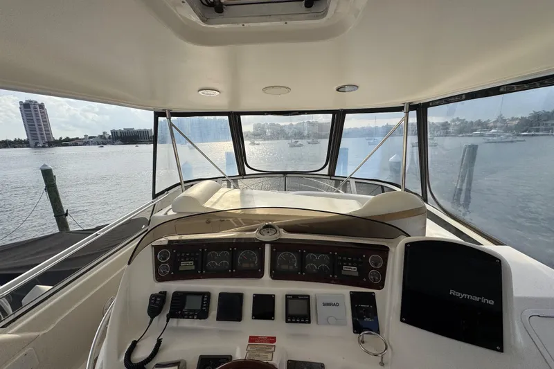 Slide: The Image of 1998 Sea Ray 480 Sedan Bridge helm with navigation equipment, overlooking marina and waterfront buildings. - 28