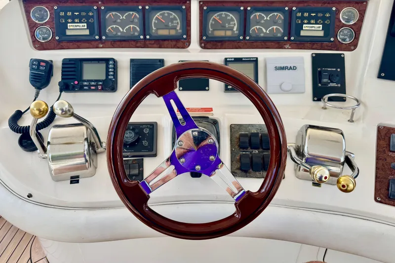 Slide: The Image of 1998 Sea Ray 480 Sedan Bridge helm with gauges, controls, and wooden steering wheel. - 30
