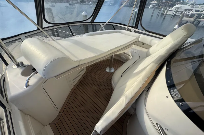 Slide: The Image of 1998 Sea Ray 480 Sedan Bridge helm with white captain chairs and wooden deck. - 31
