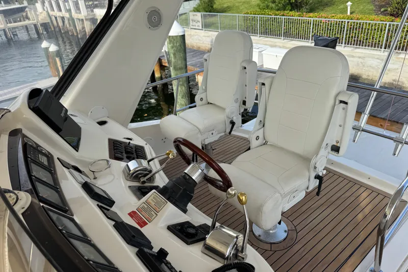 Slide: The Image of 1998 Sea Ray 480 Sedan Bridge helm with dual white captain chairs and wooden steering wheel. - 33