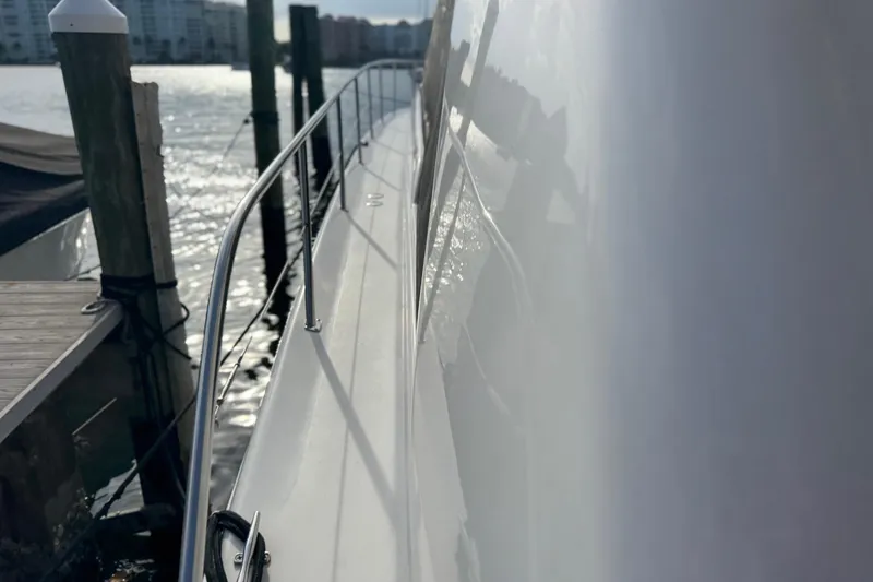 Slide: The Image of 1998 Sea Ray 480 Sedan Bridge yacht docked, side view with railing and water reflection. - 36