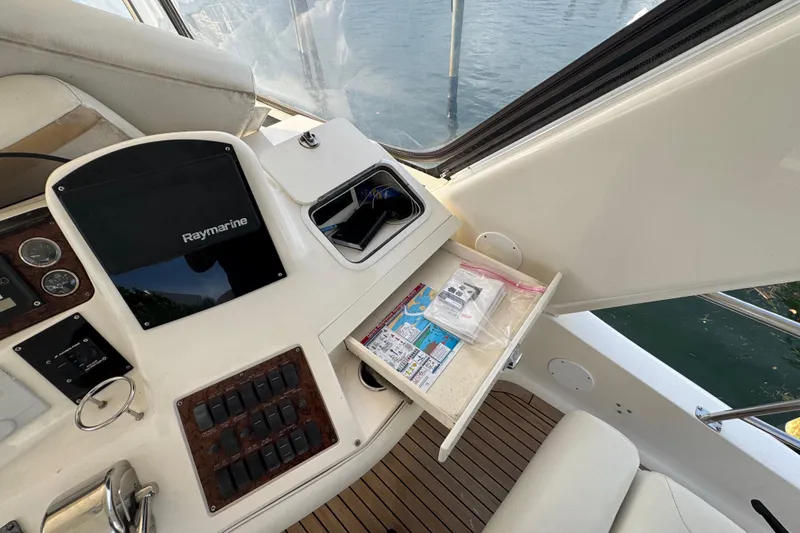 Slide: The Image of 1998 Sea Ray 480 Sedan Bridge helm with Raymarine equipment and open storage drawer. - 44
