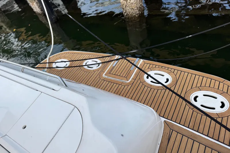 Slide: The Image of 1998 Sea Ray 480 Sedan Bridge yacht deck with wood finish, docked by water. - 57