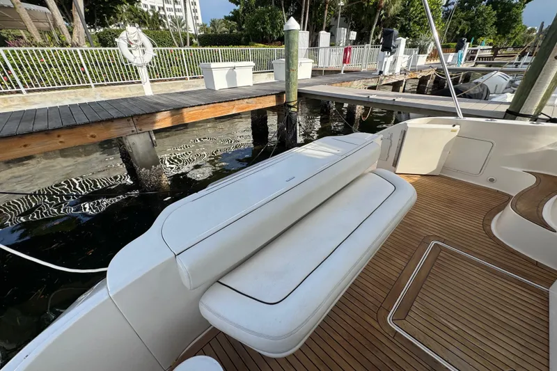 Slide: The Image of 1998 Sea Ray 480 Sedan Bridge yacht with white seating and wooden deck at a marina. - 9