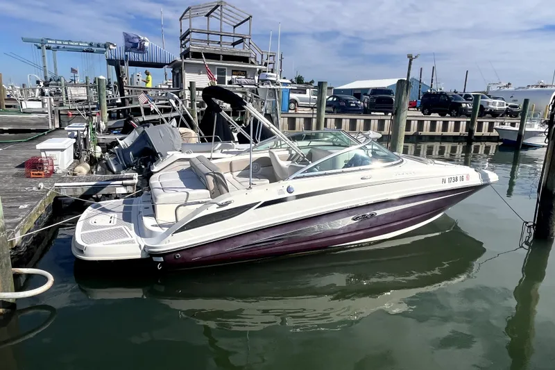 Slide: The Image of 2010 Sea Ray 220 Sundeck boat docked at marina, clear sky background. - 1