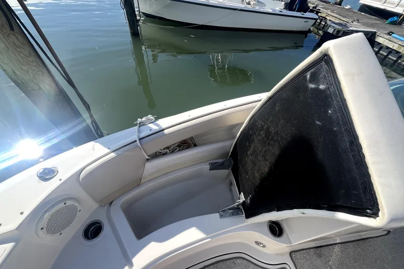 Slide: The Image of 2010 Sea Ray 220 Sundeck interior with seating and speaker, docked by the water. - 11