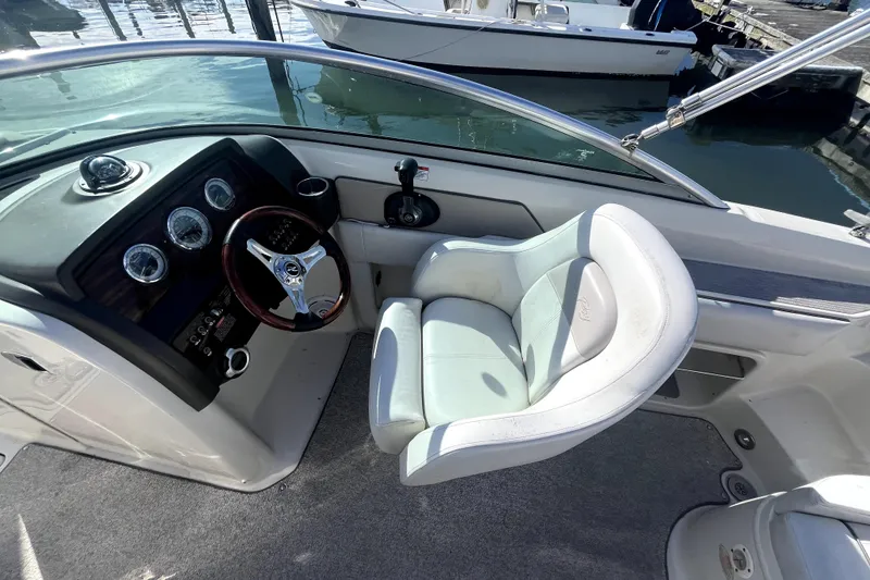 Slide: The Image of 2010 Sea Ray 220 Sundeck cockpit with steering wheel and white captain's chair. - 18
