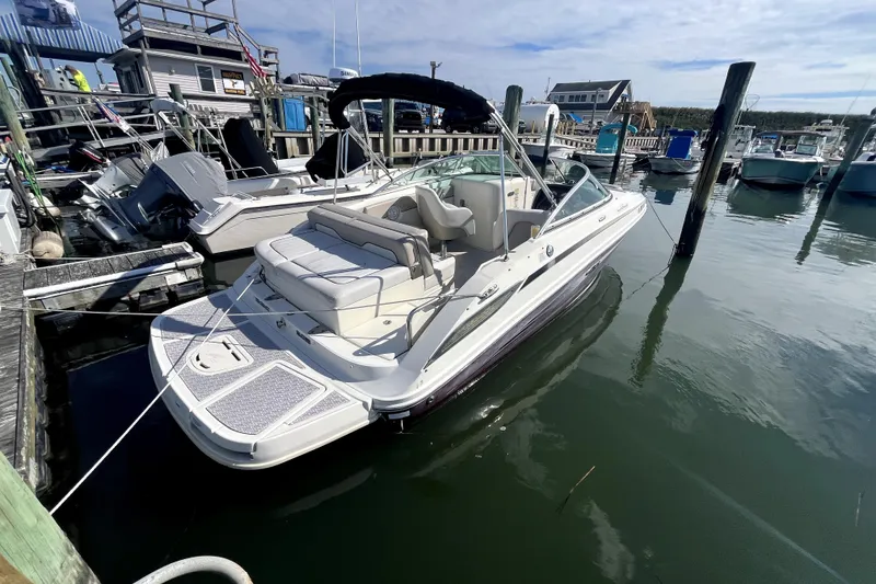 Slide: The Image of 2010 Sea Ray 220 Sundeck boat docked at a marina under a clear sky. - 2