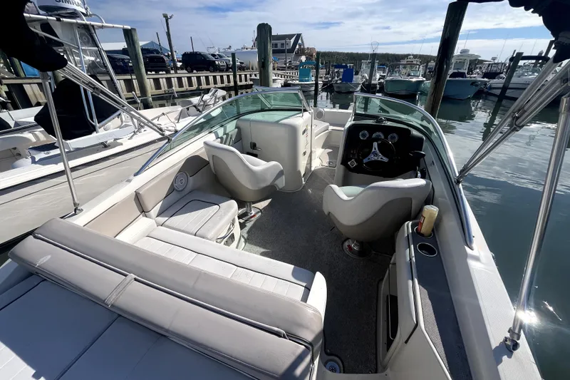 Slide: The Image of 2010 Sea Ray 220 Sundeck interior with seating and steering wheel, docked at marina. - 25