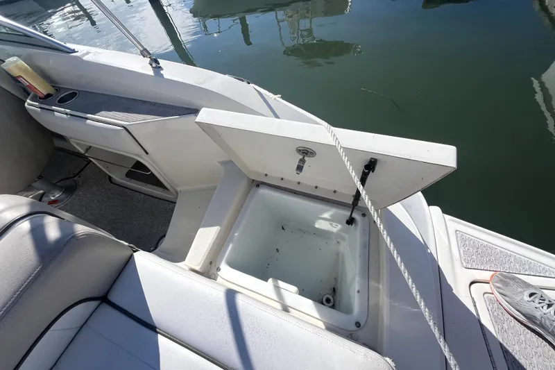 Slide: The Image of Open storage compartment on 2010 Sea Ray 220 Sundeck boat, docked by the water. - 26