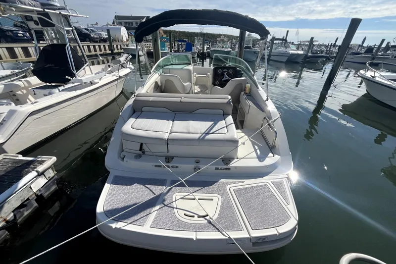 Slide: The Image of 2010 Sea Ray 220 Sundeck boat docked at marina, rear view with seating and canopy. - 3