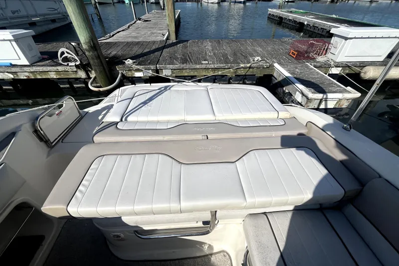 Slide: The Image of 2010 Sea Ray 220 Sundeck boat interior with white cushioned seating at dock. - 30