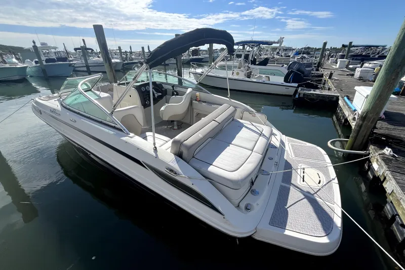 Slide: The Image of 2010 Sea Ray 220 Sundeck boat docked at marina under clear sky. - 4