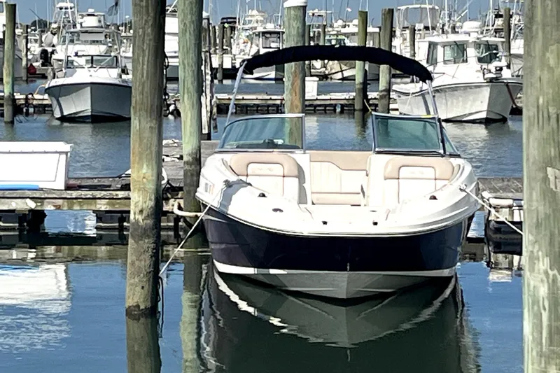 Slide: The Image of 2010 Sea Ray 220 Sundeck boat docked in a marina, surrounded by other boats. - 6