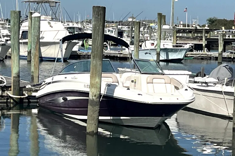 Slide: The Image of 2010 Sea Ray 220 Sundeck boat docked in a marina, surrounded by other vessels. - 7