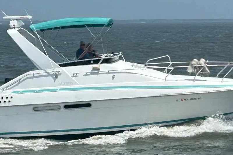 The Image of 1991 Mainship 35 Open Bridge cruising on the water with teal canopy. - 0