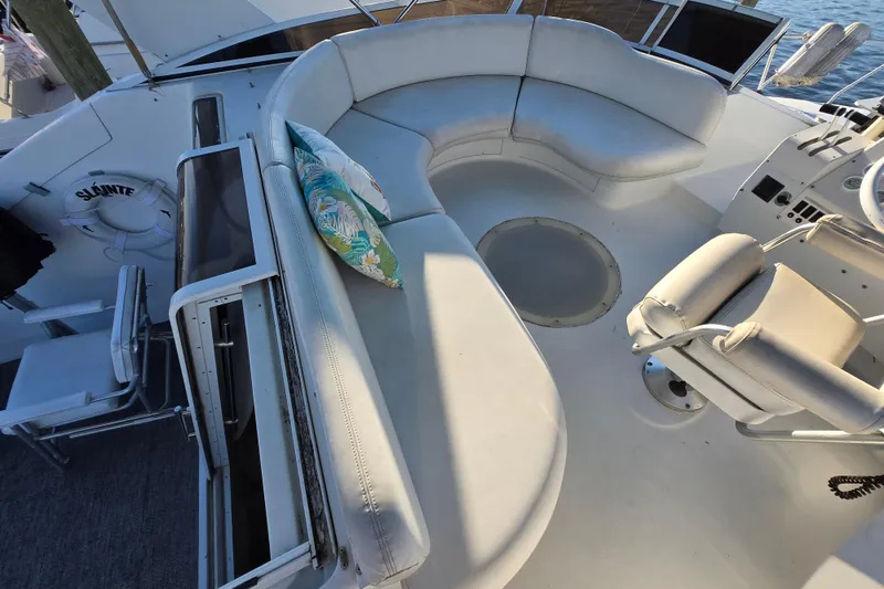 Slide: The Image of 1991 Mainship 35 Open Bridge yacht with curved seating and helm, featuring a colorful pillow. - 10