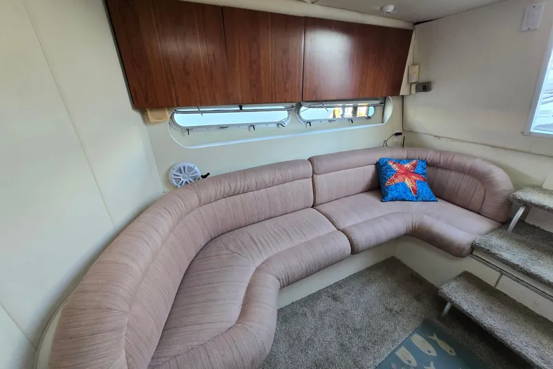 Slide: The Image of 1991 Mainship 35 Open Bridge interior with curved sofa and starfish pillow. - 17