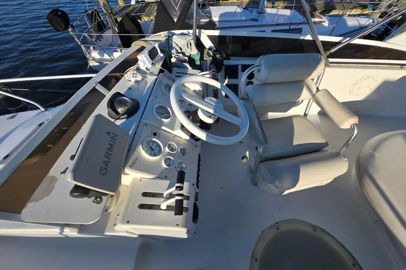 Slide: The Image of 1991 Mainship 35 Open Bridge helm with Garmin navigation, white steering wheel, and cushioned seats. - 23