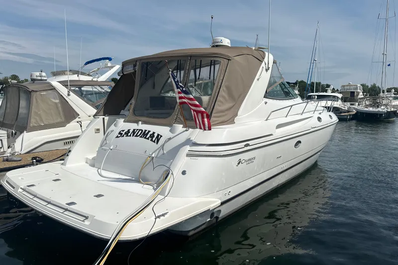 The Image of 2001 Cruisers Yachts 3870 Express docked, featuring a beige canopy and American flag. - 1