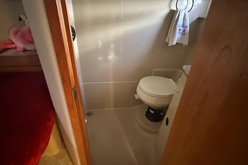 Slide: The Image of Bathroom interior of 2001 Cruisers Yachts 3870 Express, featuring a compact toilet and towel rack. - 12