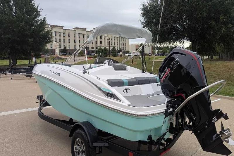 Slide: The Image of 2026 Tahoe T18 boat on trailer with outboard motor, parked outdoors. - 11