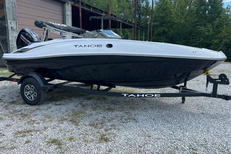 Slide: The Image of 2026 Tahoe T16 boat on trailer, parked outdoors near a wooden building. - 0