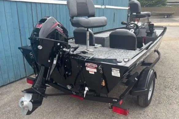 Slide: The Image of 2026 Tracker Pro 170 boat with motor, parked on a trailer near a blue building. - 2