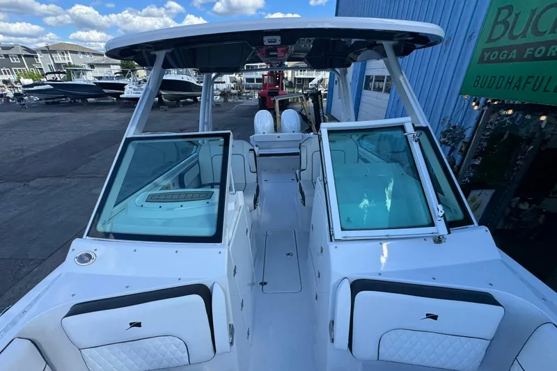 Slide: The Image of 2026 Stingray 259 DC boat with open deck, docked near a blue building. - 20