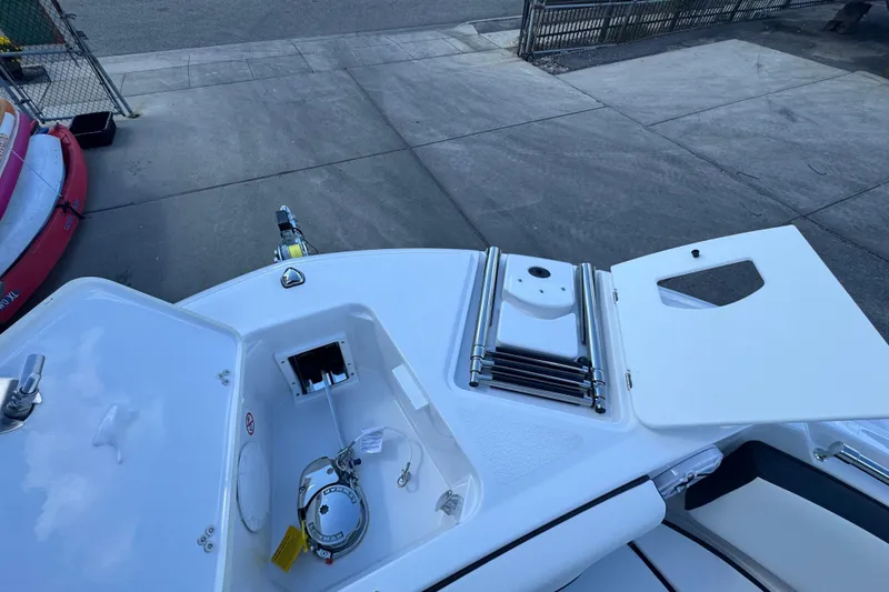 Slide: The Image of 2026 Stingray 259 DC boat deck with open storage compartments and ladder. - 21